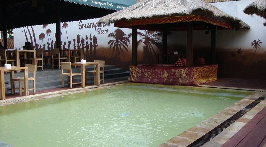 SmaraPura Resto patio with thatched roof pavilions and an outdoor pool, tropical mural on the wall