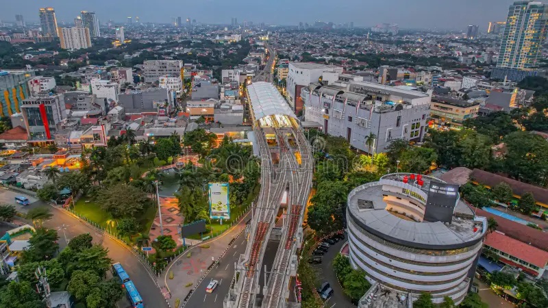 Aerial view of urban roads and rail lines beside a large circular building in a city skyline