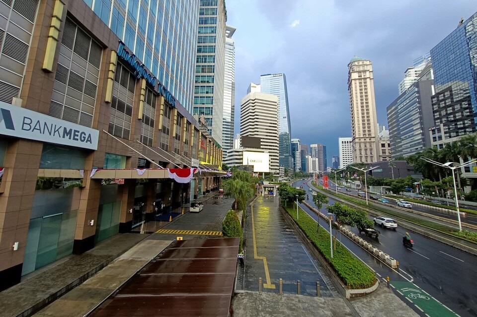 BankMega storefront sign on a city street with skyscrapers, traffic lanes, and road barriers in view