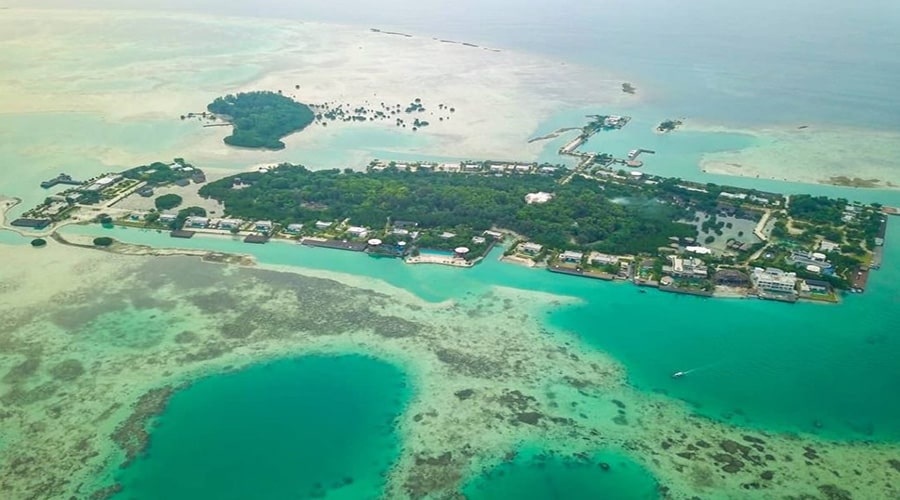 Aerial view of a tropical island with turquoise waters, docks, and small buildings along the shore