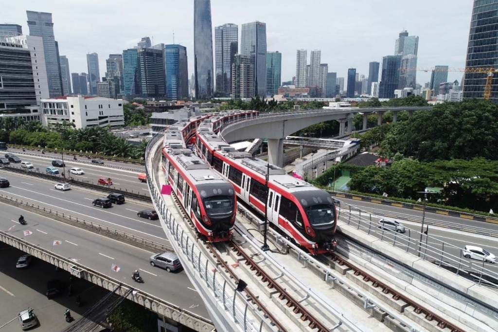 High-speed red trains on elevated tracks in a modern city skyline with highways and skyscrapers