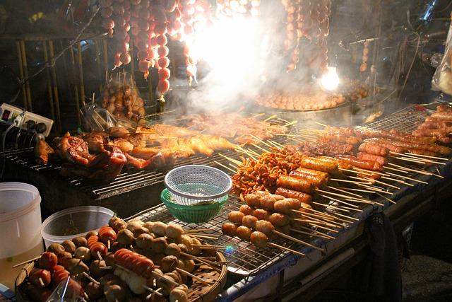 Outdoor barbecue grill with sizzling skewers of chicken, sausages, and vegetables under smoke and flames