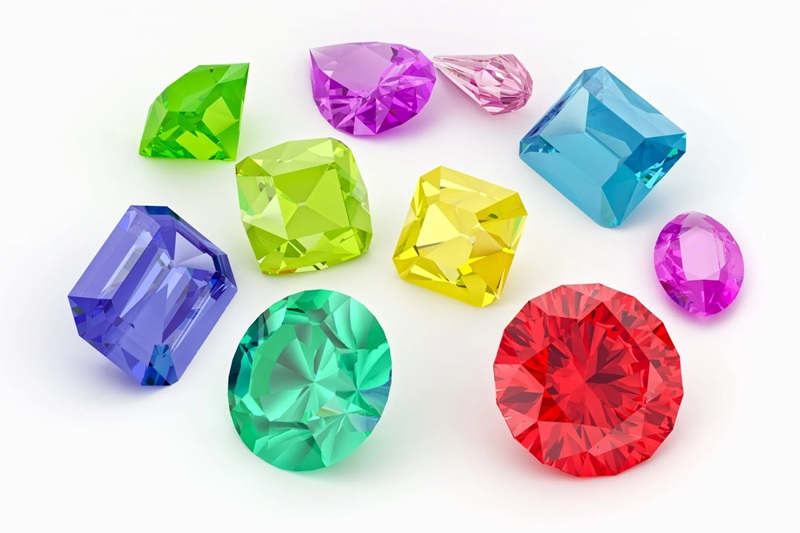 Colorful faceted gemstones, including green, blue, purple, yellow, and red crystals on white background