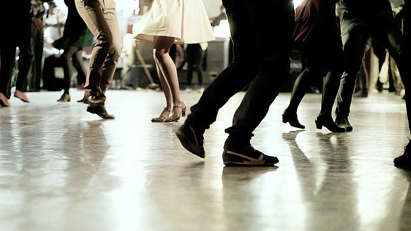 People dancing on a dance floor, close-up of legs and shoes during a lively party.