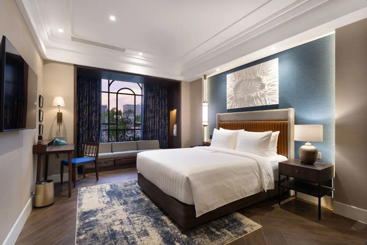 Modern bedroom interior with king bed, blue accent wall, large window curtains, and decorative rug