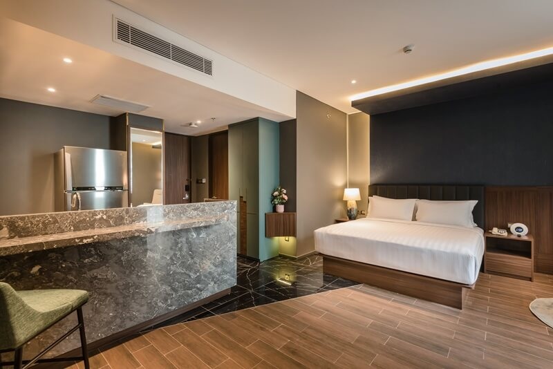 Modern luxury hotel suite with king bed, stone bathroom vanity, and warm ambient lighting in bedroom