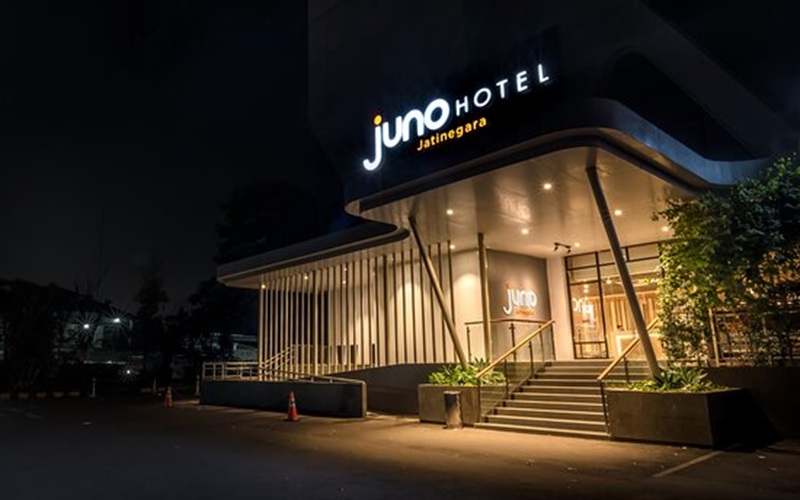 juno hotel jatingara entrance at night with illuminated signage, modern facade, steps, and landscaped plants