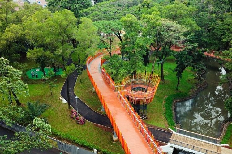 A winding orange walkway with metal railing through lush green park landscaping and pond views from above