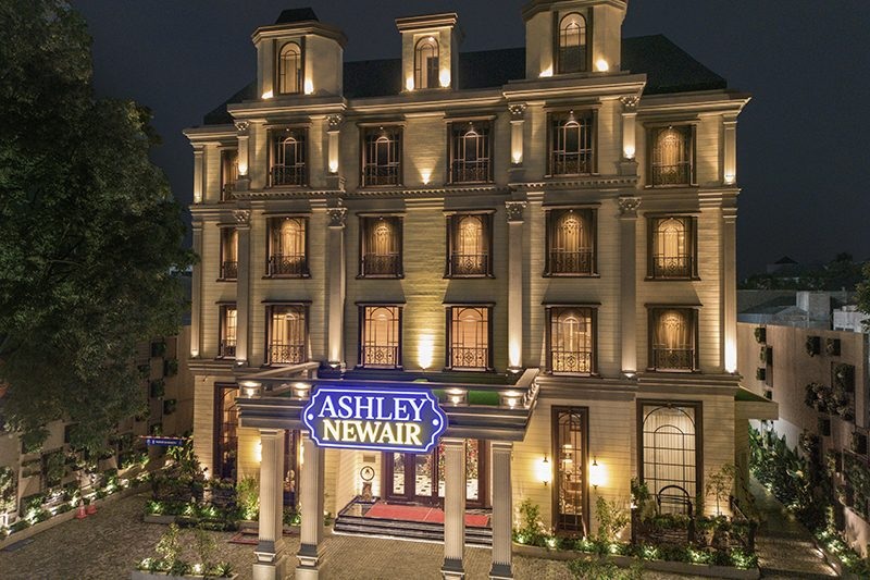 Ashley Newair sign on a warmly lit building facade at night with classic windows and columns