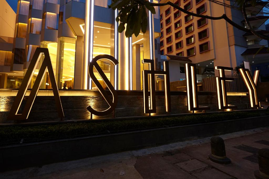 Modern hotel entrance signage with illuminated geometric letters and columns at night, surrounded by tall buildings