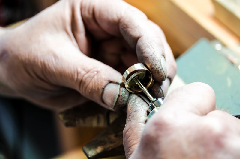 Close-up of hands using a wrench to adjust a small metal fitting on a pipe or valve