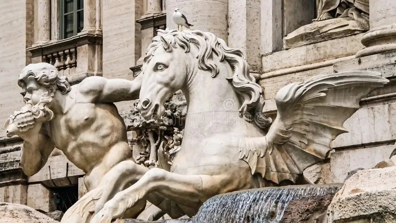 Baroque marble fountain statue of a rearing horse with flowing mane and cherub in front of ornate building columns