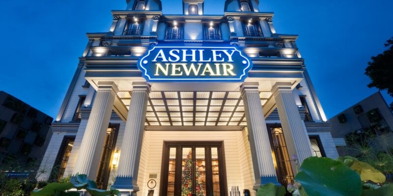 Ashley Newair building entrance with glowing sign, tall white columns, and evening blue sky