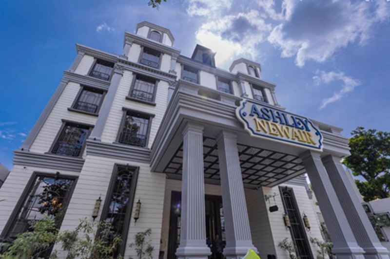 Asbury Newhall building façade with large columns and sign against blue sky with clouds