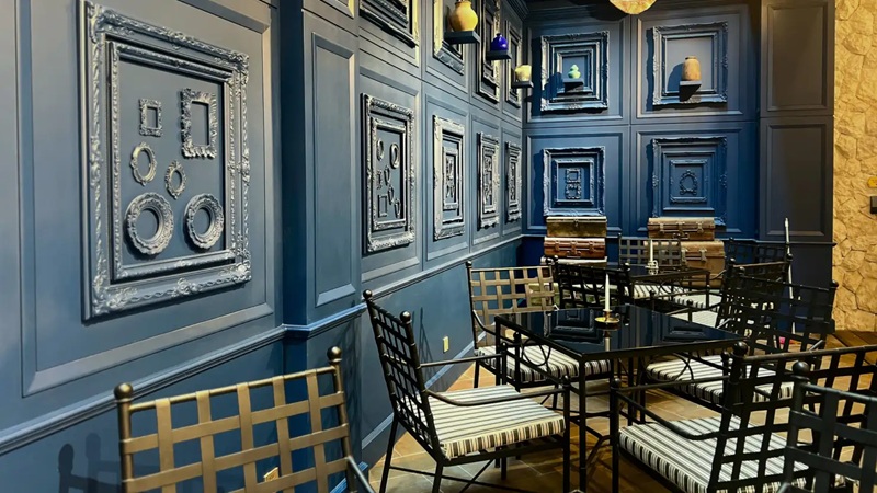 Elegant blue paneled room with framed art panels and rows of black chairs and tables, modern interior decor