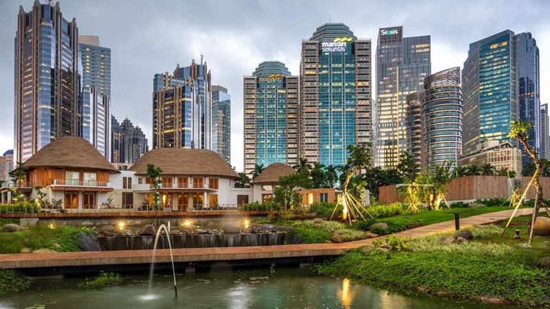 Riverside hotel with modern skyline towers and landscaped garden, fountains at dusk in the city
