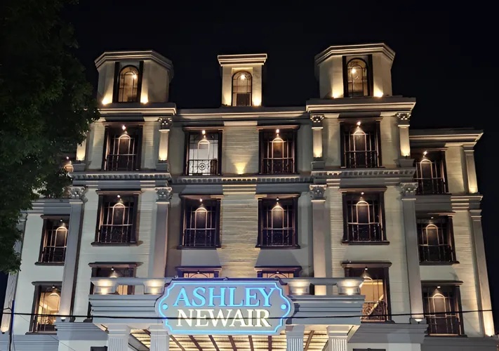 Ashley Newair illuminated building facade at night with storefront sign and tall columns, lit windows and arches