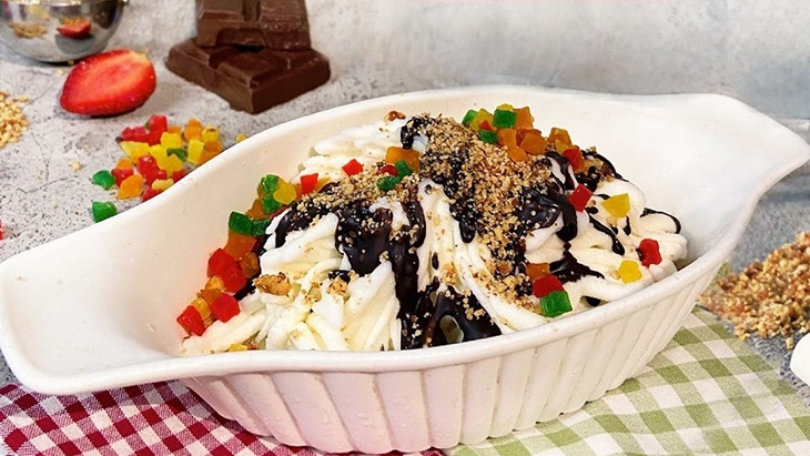 Spaghetti in a white takeout bowl topped with dark sauce, sesame, and diced bell peppers on a tablecloth