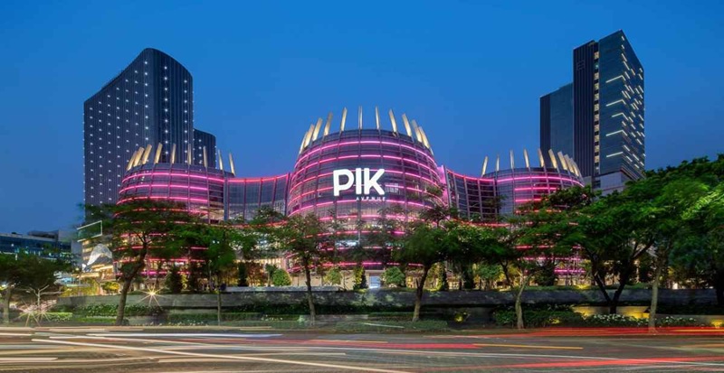PIK Avenue mall at dusk with illuminated pink LED facade and modern skyscrapers under blue sky