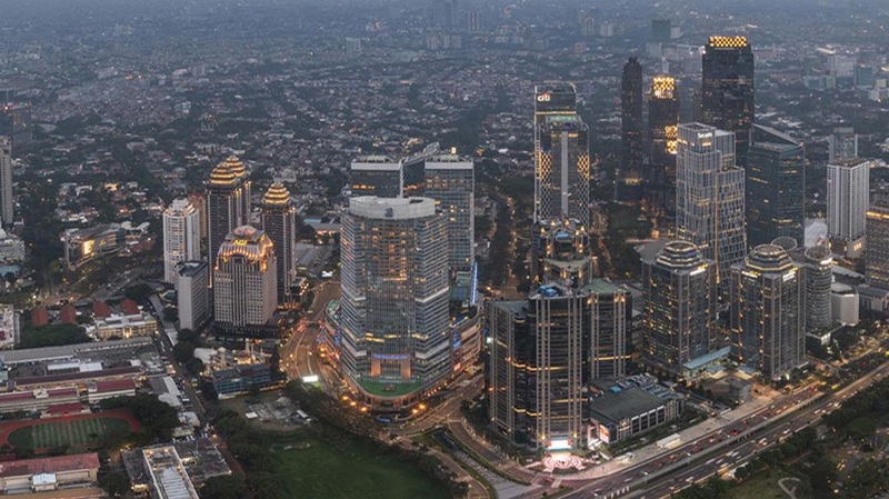 Aerial view of Jakarta’s skyline with skyscrapers, city streets, and the evening glow over the cityscape