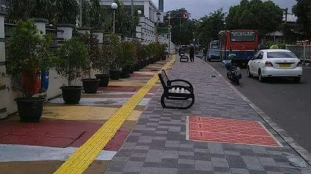 Empty street curb with red pedestrian crossing markings, parking lane, and vehicles in daylight