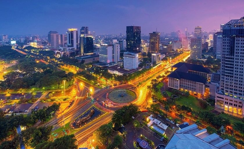 Bangkok city skyline at dusk with illuminated roads, buildings, and a central roundabout traffic circle