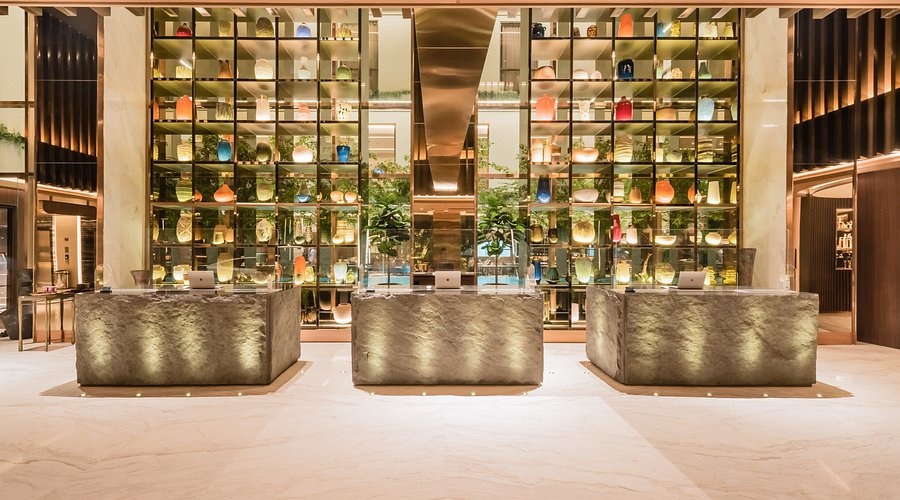 Luxury hotel bar with illuminated glass shelves and glowing bottles behind metallic counters