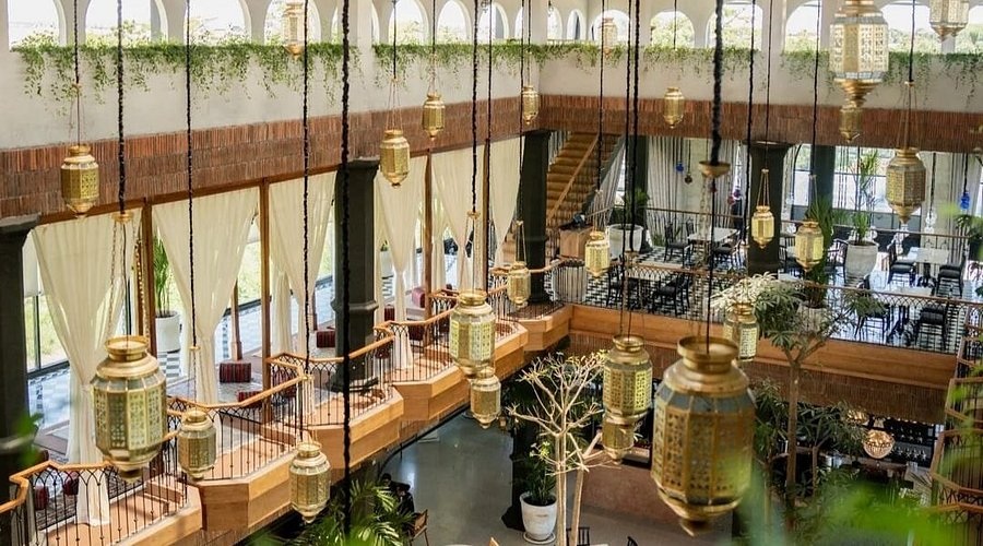 Moroccan-style lanterns hanging over an elegant event hall with arched windows and stacked seating