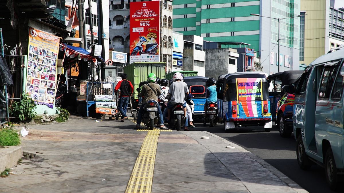 Street market with scooters and cars in front of large building walls and promotional banners in Indonesia
