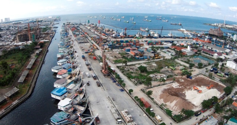 Aerial view of a harbor with shipping docks, cargo containers, and boats along the riverfront