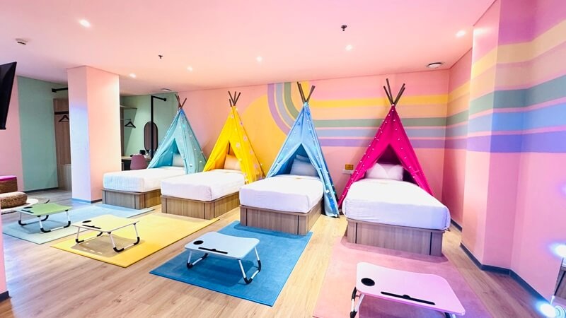 Colorful kids playroom with tents, padded floor mats, and bright geometric wall art, exercise and lounge area