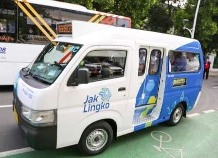 White and blue shuttle van parked outdoors with “Jak Lingko” branding on the side and front