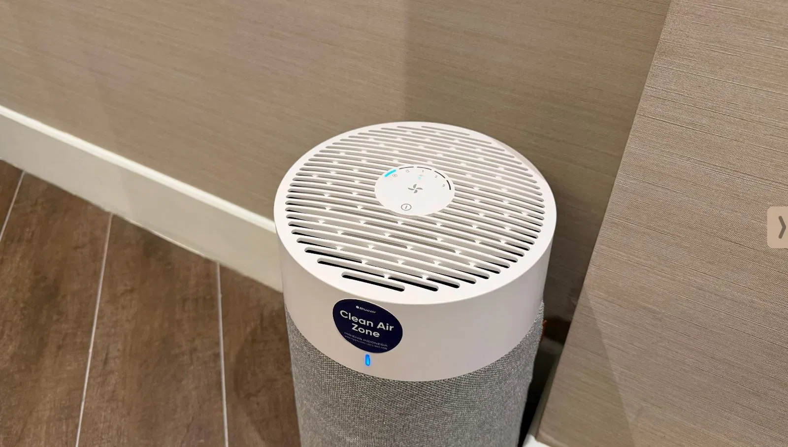 Clean Air Zone air purifier on floor with blue indicator light in modern interior room