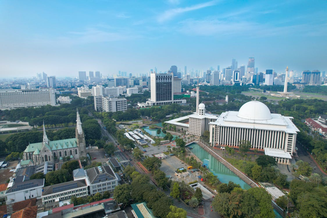 Aerial view of city skyline with Bangkok riverfront buildings, modern skyscrapers, green parks, and a large white domed complex