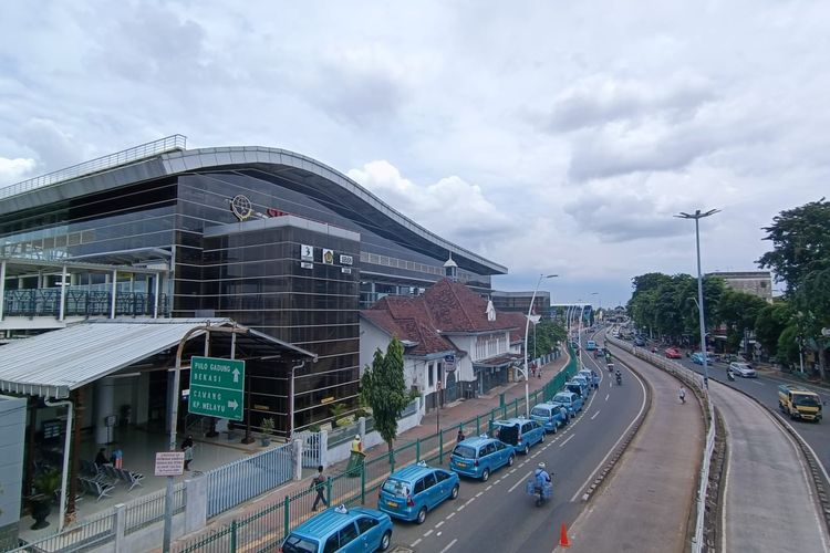 Urban street view with parked cars and a modern building facade, buses and traffic on the road