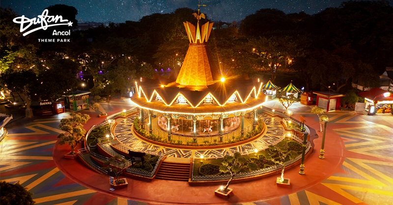 Burning Man-themed amusement park ride at night with illuminated central carousel and light show across grounds