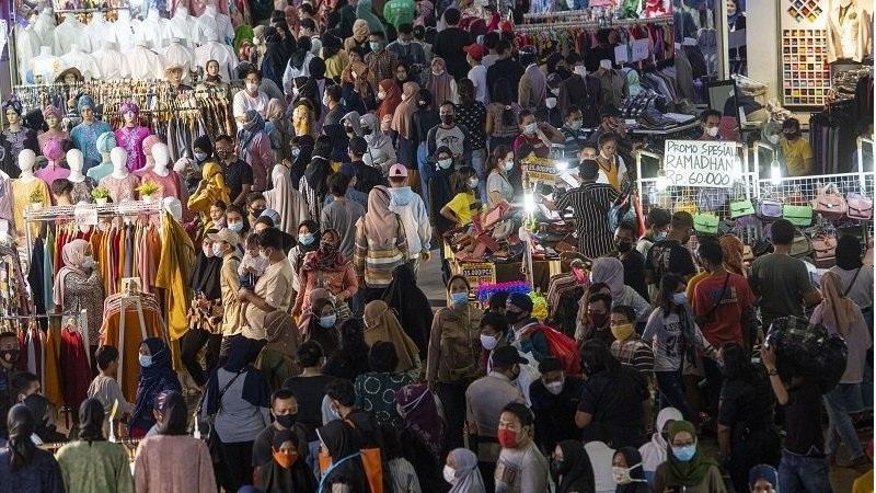 Crowded market stalls packed with shoppers wearing face masks and Ramadan promotional signs