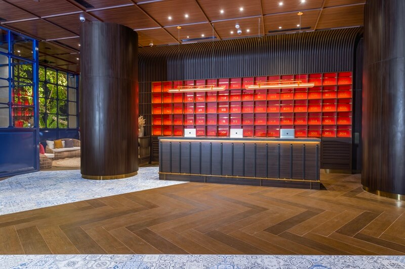 Modern lobby mailboxes with glowing red backlit rows and wood columns, warm lighting interior
