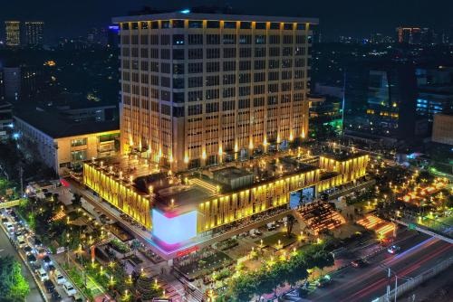 Aerial night view of a brightly lit hotel building and surrounding city streets with traffic lights