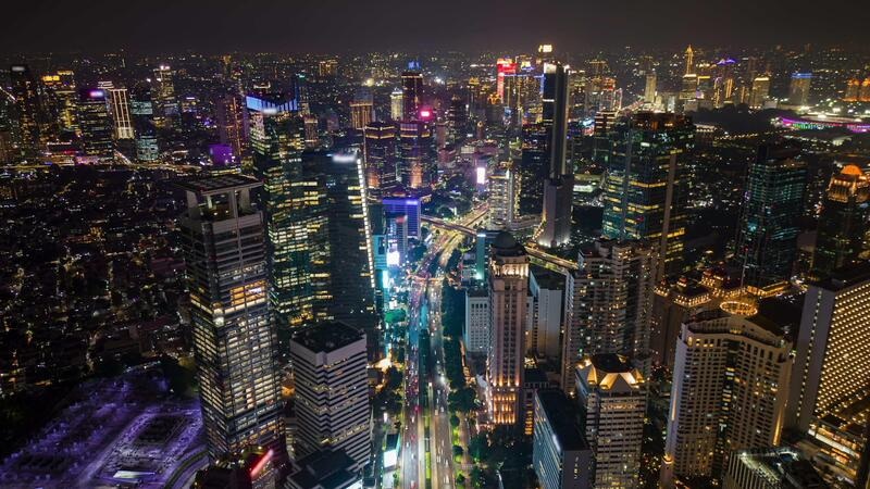 Night skyline view of downtown city with illuminated skyscrapers and busy streets below