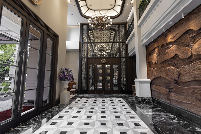 Elegant indoor foyer with black door frames, marble tile floor, chandelier, and ornate wall panels
