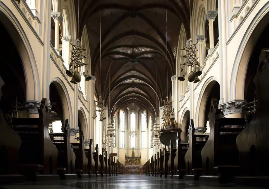 Interior view of a grand cathedral with vaulted arches, towering columns, and rows of organ pipes and instruments