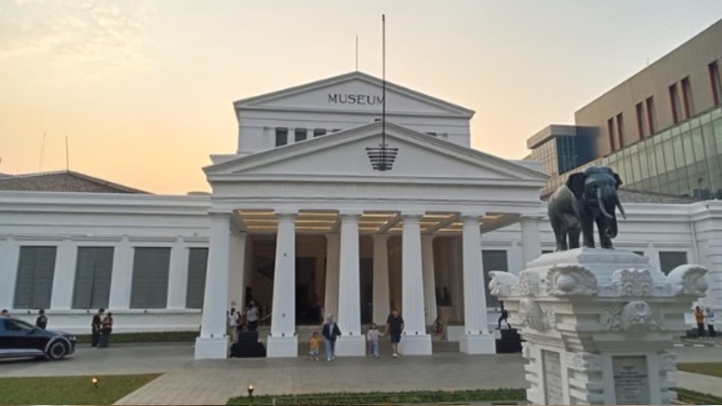 Museum building with tall white columns and bronze elephant statue in front, outdoor evening scene