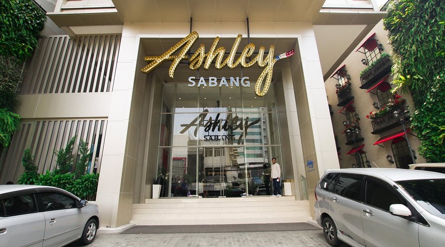 Holiday Sabang storefront entrance with illuminated sign, glass doors, and parked cars in front