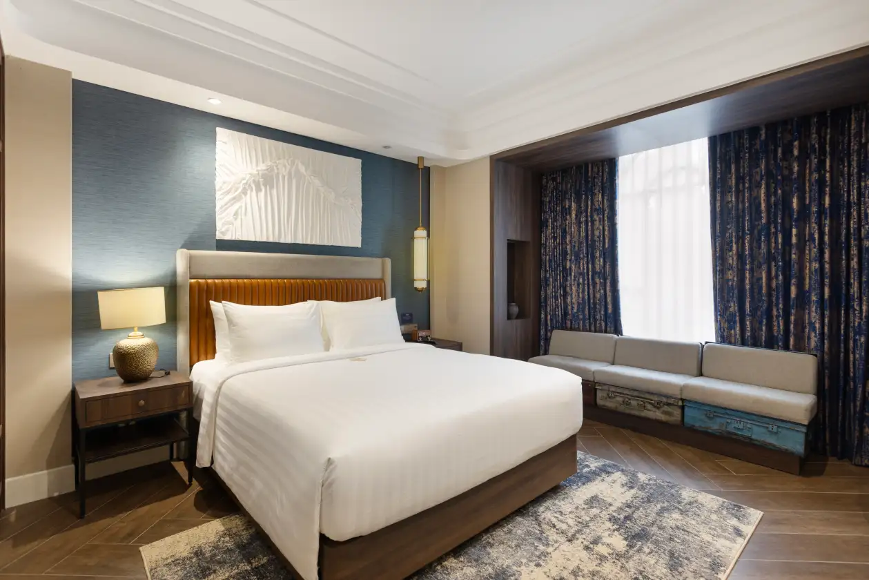 Modern bedroom with king bed, gold headboard, bedside lamps, and blue patterned curtains