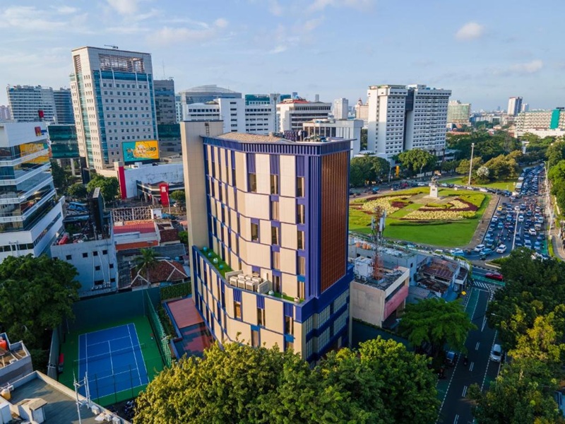 Urban hotel building with rooftop gardens and tennis court in city skyline view