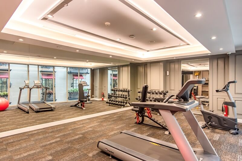Modern gym interior with treadmills, weight machines, and dumbbell racks under bright ceiling lights