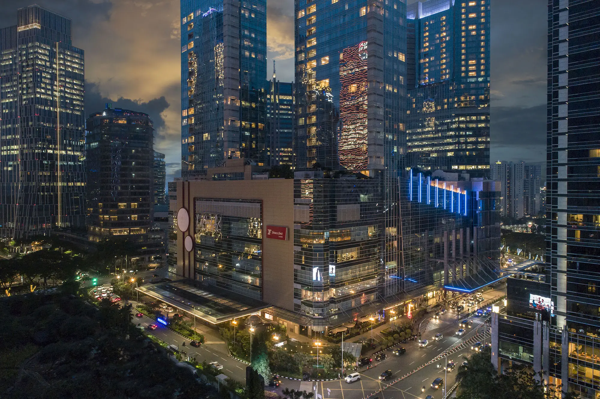 aerial night view of illuminated city skyscrapers around a modern shopping mall