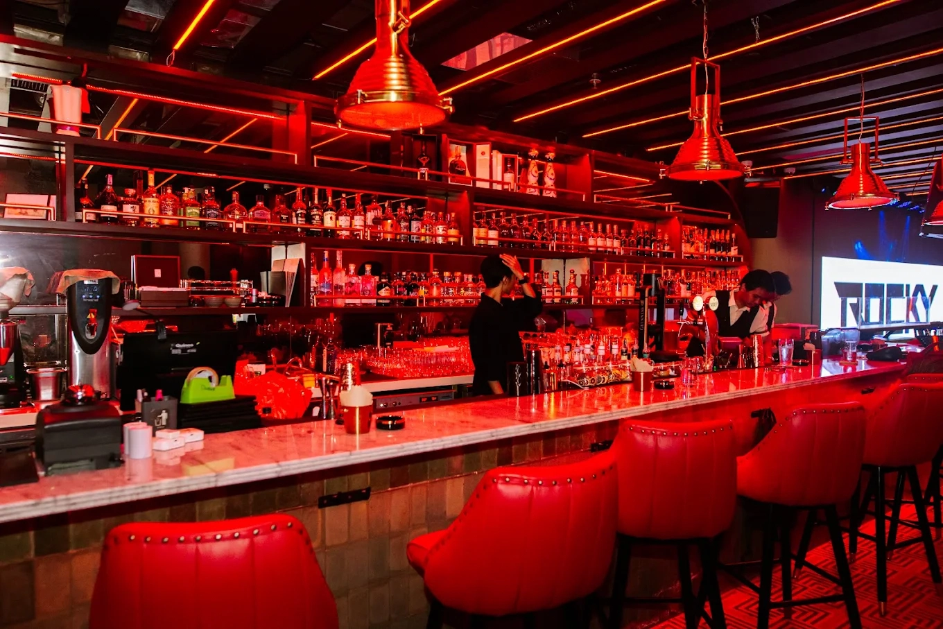 bar interior with red ambient lighting and red leather stools