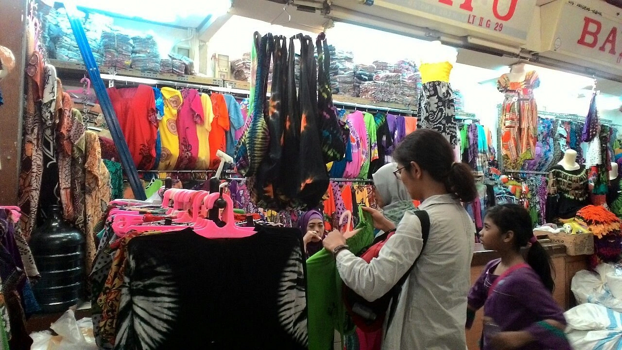 clothing stall in a market filled with colorful batik and printed dresses